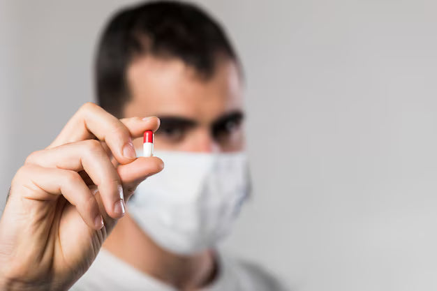 Close-up of an adult man holding PLT-NORM Ayurvedic capsule for dengue recovery, natural herbal medicine to boost platelet count safely.