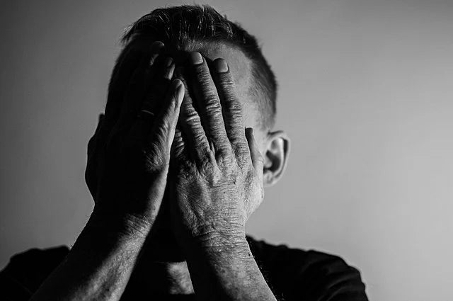 A grayscale photo of a man covering his face with his hands, illustrating deep emotional distress, persistent sadness, and the hidden pain of depression—perfect for a blog post about depression symptoms, causes, and natural treatment.