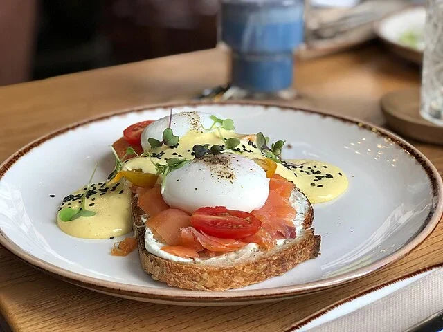 Healthy breakfast with poached eggs, smoked salmon, and fresh vegetables on whole-grain toast – a balanced meal to calculate how many calories you need per day for weight loss, maintenance, or muscle gain.