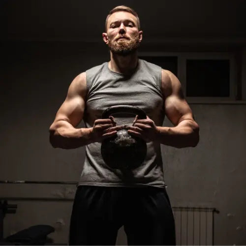 Muscular man in a gym holding a kettlebell, showcasing strength, muscle growth, and safe resistance training as discussed in the science of building muscle.